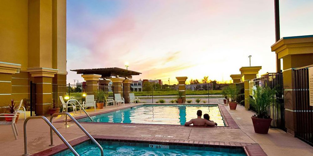 Couple lounging in a pool at sunset